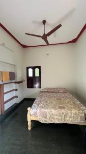 a bedroom with a bed with a ceiling fan at JM Arunachala Stays in Tiruvannāmalai