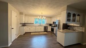 a large kitchen with white cabinets and a wooden floor at The Massillon Retreat! in Massillon +22 photos