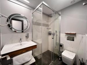 a bathroom with a shower and a sink and a mirror at ERTAN OTEL in Çeşme