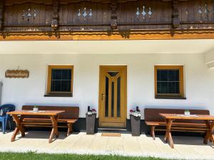 two wooden tables in front of a building with a door at Haus Deutschmann in Wenns