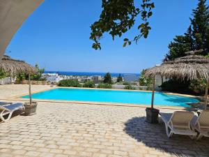 a swimming pool with two chairs and umbrellas at Dar El kharrouba in Hammamet Nord