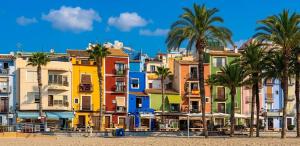 a group of houses on the beach with palm trees at La casa amarilla de Luis y Eileen in Villajoyosa
