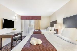 a hotel room with two beds and a desk at Days Inn by Wyndham Sylvan Lake in Sylvan Lake +80 photos