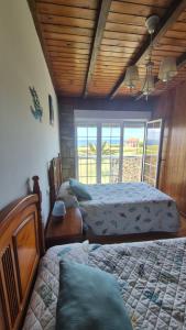 a bedroom with two beds and a wooden ceiling at La Morada del CABO PEÑAS Folu - Gozón - Luanco in Ferrero
