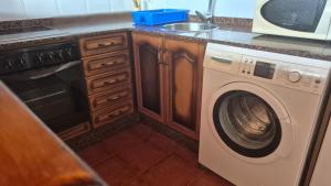 a kitchen with a washing machine and a microwave at La Morada del CABO PEÑAS Folu - Gozón - Luanco in Ferrero