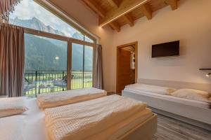 two beds in a room with a large window at Unterbergerhof - Escape daily life - Enjoy nature - Explore more with activeCARD Sterzing in Val di Vizze