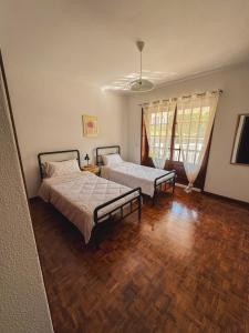 a bedroom with two beds and a wooden floor at Titi's House in Gulpilhares