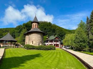 a large building with a grass field in front of it at CAZARE TURISM PRISLOP in Haţeg