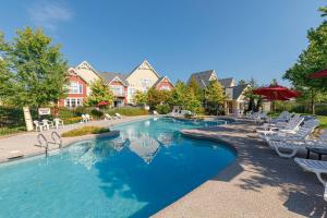 a large swimming pool with chairs and umbrellas at Rivergrass by Property Valet in Blue Mountains