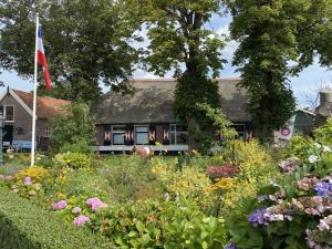 a house with a flag and a garden with flowers at B&B De Kaagse Boer in Kaag