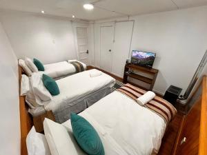 a small room with two beds and a television at The White House Hostel in Puerto Natales