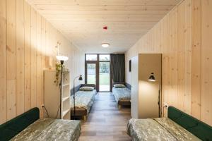 a hospital room with three beds and wooden walls at Svencelė Resort in Svencelė