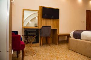 a hotel room with a bed and a desk with a television at Valero Hôtel in Cotonou