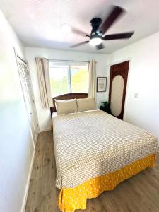 a bed in a bedroom with a ceiling fan at Happy Hill Inn in Kailua-Kona