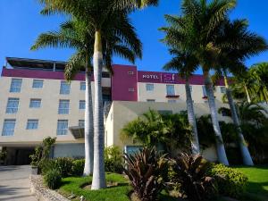 a hotel with palm trees in front of it at Hotel SI Chapala in Chapala
