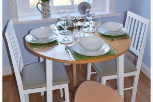 a dining room table with chairs and a wooden table with plates and glasses at Largo Bay - Harbour Hideaway in Leven