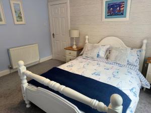 a bedroom with a white bed with a blue comforter at Largo Bay - Harbour Hideaway in Leven