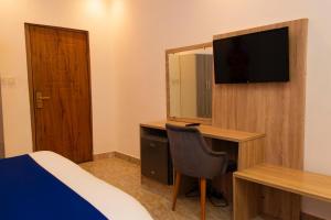 a bedroom with a bed and a desk with a television at Valero Hôtel in Cotonou