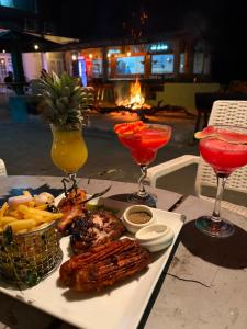 a table with a plate of food and two cocktails at Zentara Ella by silkfive in Ella