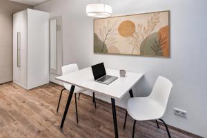 a white table with white chairs and a laptop on it at MIILOX Apartments Dresden in Dresden +16 photos