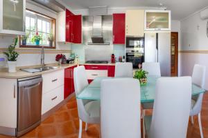 a kitchen with red cabinets and a glass table and white chairs at Casa do Lago guest house in Espinho