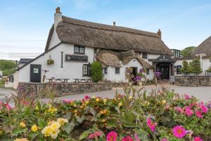 a thatched cottage with flowers in front of it at 3 Bed in Braunton oc-soufar in Braunton