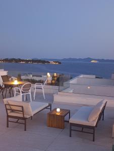 a patio with chairs and tables and a view of the water at M&M Luxury Apartments in Petrcane