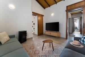 a living room with a blue couch and a tv at Villa Amada in Vega de San Mateo