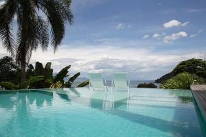 duas cadeiras brancas sentadas ao lado de uma piscina em Casa Mar Paraty em Paraty