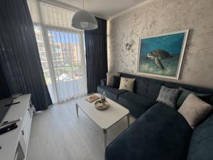 a living room with a blue couch and a table at Turtle Apartment Sunny Beach in Sunny Beach