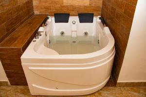 a white bath tub in a bathroom with brown tiles at Valero Hôtel in Cotonou