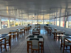 a dining room with tables and chairs and windows at Hotel Mello in Cascavel