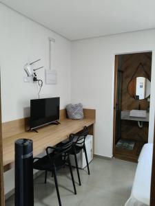 a room with a desk with a television and chairs at Suíte 15 in Pontal do Paraná