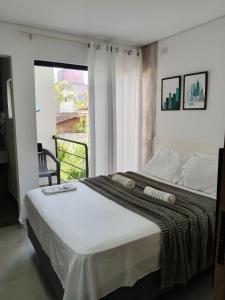 a bedroom with a large bed with a balcony at Suíte 15 in Pontal do Paraná