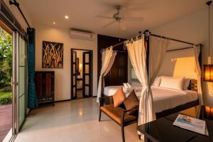a bedroom with a bed and a chair in a room at Emerald Pool Villa Lush Villa On A Sunny Island in Nai Harn Beach +50 photos