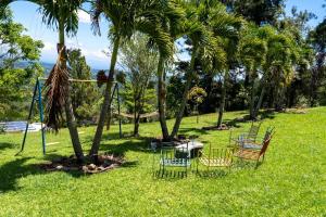 a park with chairs and palm trees and a swing at Altura secreta in Jarabacoa +30 photos