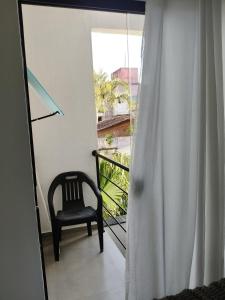 a chair sitting on a balcony with a window at Suíte 15 in Pontal do Paraná