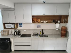 a kitchen with white cabinets and a sink and a stove at Suíte 15 in Pontal do Paraná