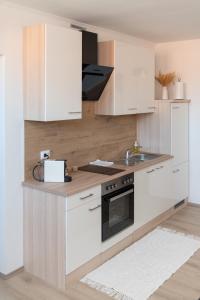 a kitchen with white cabinets and a sink at La casa de papel Apartment in Bjelovar +10 photos