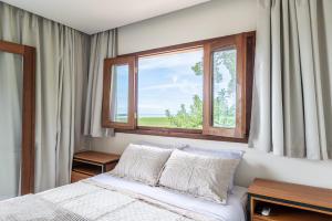 a bedroom with a bed and a large window at River & Ocean View House with Pool in Igarassu
