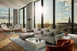 a living room with a couch and a large window at NH Collection Copenhagen in Copenhagen