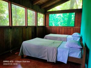 two beds in a room with two windows at Centro Ecoturístico Cueva del Tejón in Champa