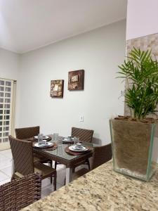 a dining room with a table with chairs and a plant at Casa Completa próxima ao Centro in Passos