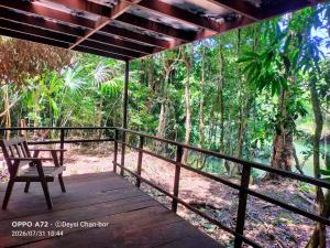 a wooden porch with a chair on a deck at Centro Ecoturístico Cueva del Tejón in Champa