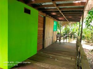 a wooden porch with a green wall and a bench at Centro Ecoturístico Cueva del Tejón in Champa