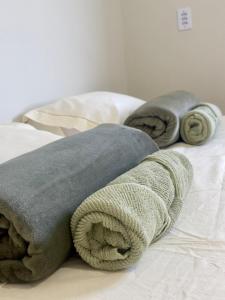 two blankets and pillows on top of a bed at Casa Completa próxima ao Centro in Passos