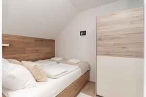 a bedroom with a white bed with a wooden headboard at La casa de papel Apartment in Bjelovar