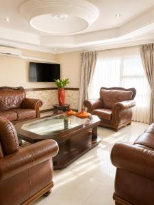 a living room with leather furniture and a flat screen tv at Azania Bed & Breakfast in Meyerton