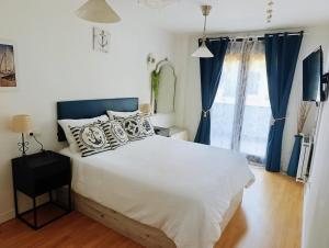 a bedroom with a large white bed with blue curtains at El Llambrion in Posada de Llanes