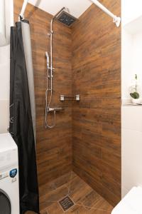 a shower in a bathroom with a wooden wall at La casa de papel Apartment in Bjelovar